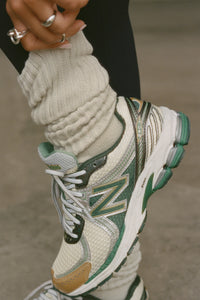 Close up front view of model adjusting the  slouchy off white Scrunch Sock with extra long ribbed cuffs