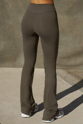 Back view of model from the waist down posing in the full length bootcut sueded carob Second Skin Bootcut Legging with a wide v-shaped waistband and split detail at the leg opening
