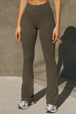 Front view of model from the waist down posing in the full length bootcut sueded carob Second Skin Bootcut Legging with a wide v-shaped waistband and split detail at the leg opening