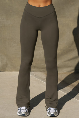 Front view of model from the waist down posing in the full length bootcut sueded carob Second Skin Bootcut Legging with a wide v-shaped waistband and split detail at the leg opening