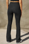 Back view of model from the waist down posing in the full length bootcut sueded onyx Second Skin Bootcut Legging with a wide v-shaped waistband and split detail at the leg opening