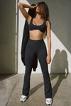 Full body front view of model posing in the full length bootcut sueded onyx Second Skin Bootcut Legging with a wide v-shaped waistband and split detail at the leg opening