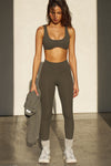 Full body front view of model posing in the full length and high-waisted sueded carob Second Skin Legging with a wide, v-shaped waistband