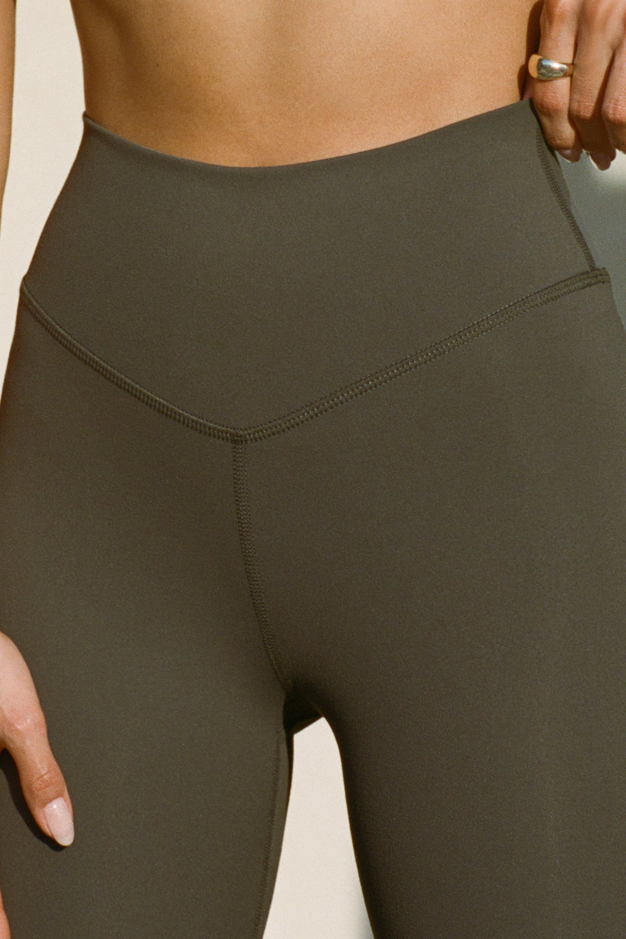 Close up detailed front view of model from the waist down posing the full length and high-waisted sueded carob Second Skin Legging with a wide, v-shaped waistband