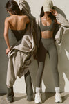 Two models posing in Joah Brown sueded carob sets, including the Contour Bra and Second Skin Legging in sueded carob