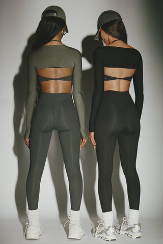 Back view of two models posing in the full length and high-waisted sueded essex and sueded onyx Second Skin Leggings with a wide, v-shaped waistband