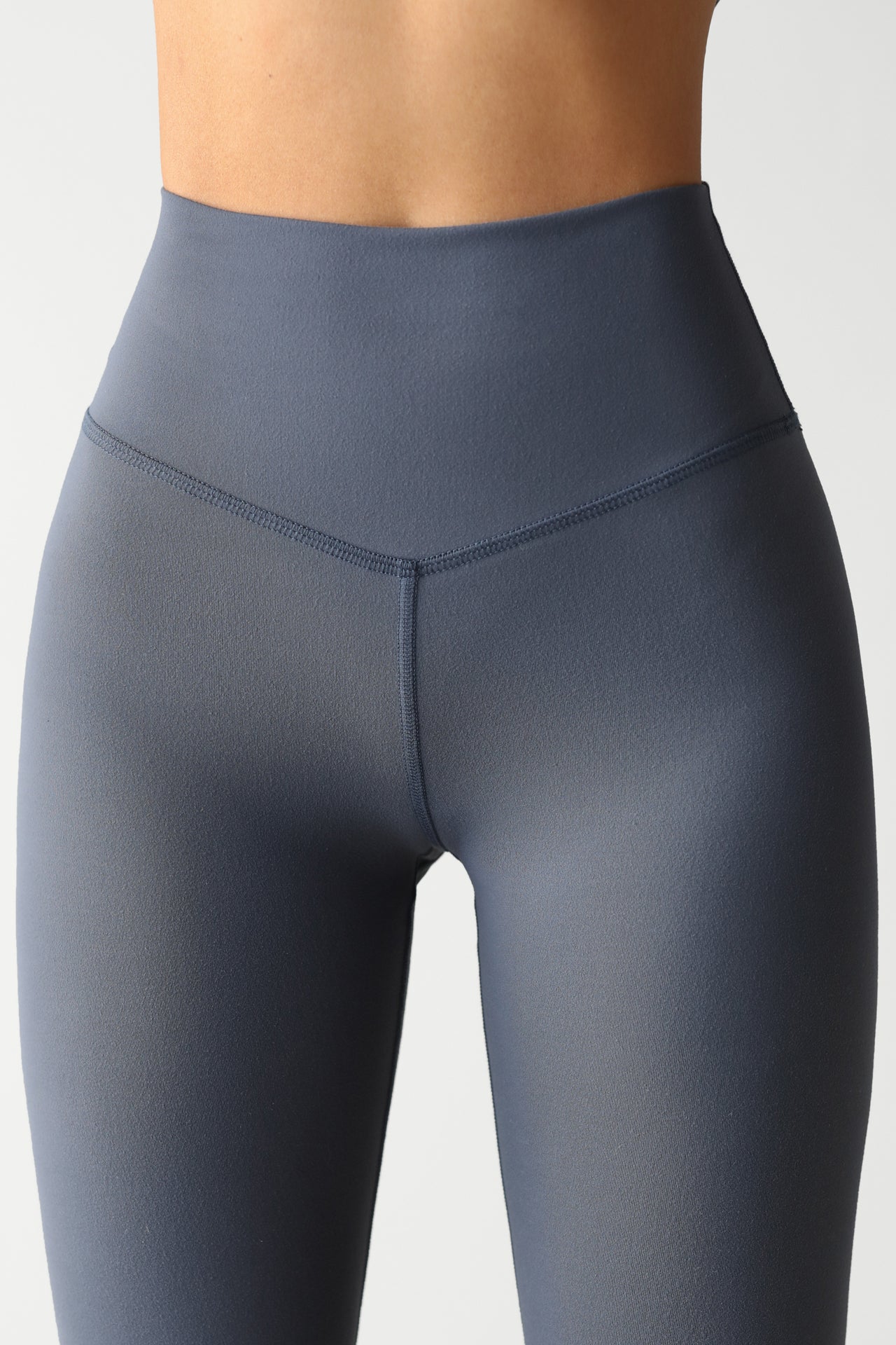 Close up detail front view of model from the waist down posing the full length and high-waisted sueded navy Second Skin Legging with a wide, v-shaped waistband