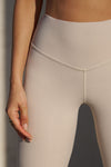 Close up detail front view of model from the waist down posing in the full length and high-waisted sueded yuma Second Skin Legging with a wide, v-shaped waistband