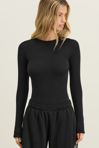 Front view of model posing in fitted black flexrib Sheer Back Long Sleeve top with a crew neckline and sheer mesh back panel.