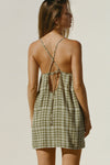 Back view of model posing in the lightweight orchard gauze Shift Mini Dress with a scoop neckline, front keyhole detail and open back with adjustable straps and a tie closure
