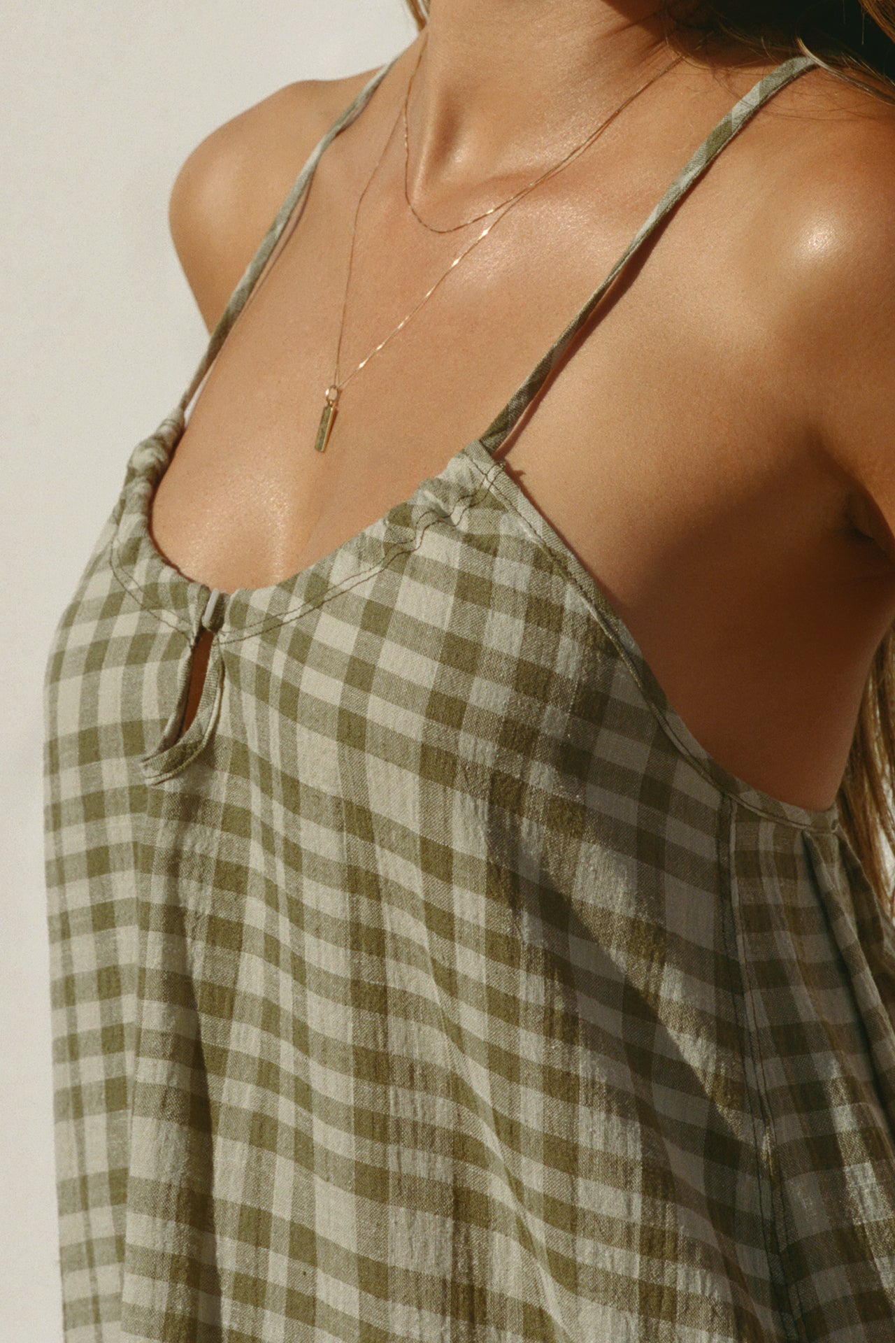 Close up detail side view of model posing in the lightweight orchard gauze Shift Mini Dress with a scoop neckline, front keyhole detail and open back with adjustable straps and a tie closure