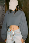 Front view of model posing in the cropped relaxed fit evergreen cotton slouchy crop long sleeve top with a crew neckline, dropped shoulders and oversized sleeves