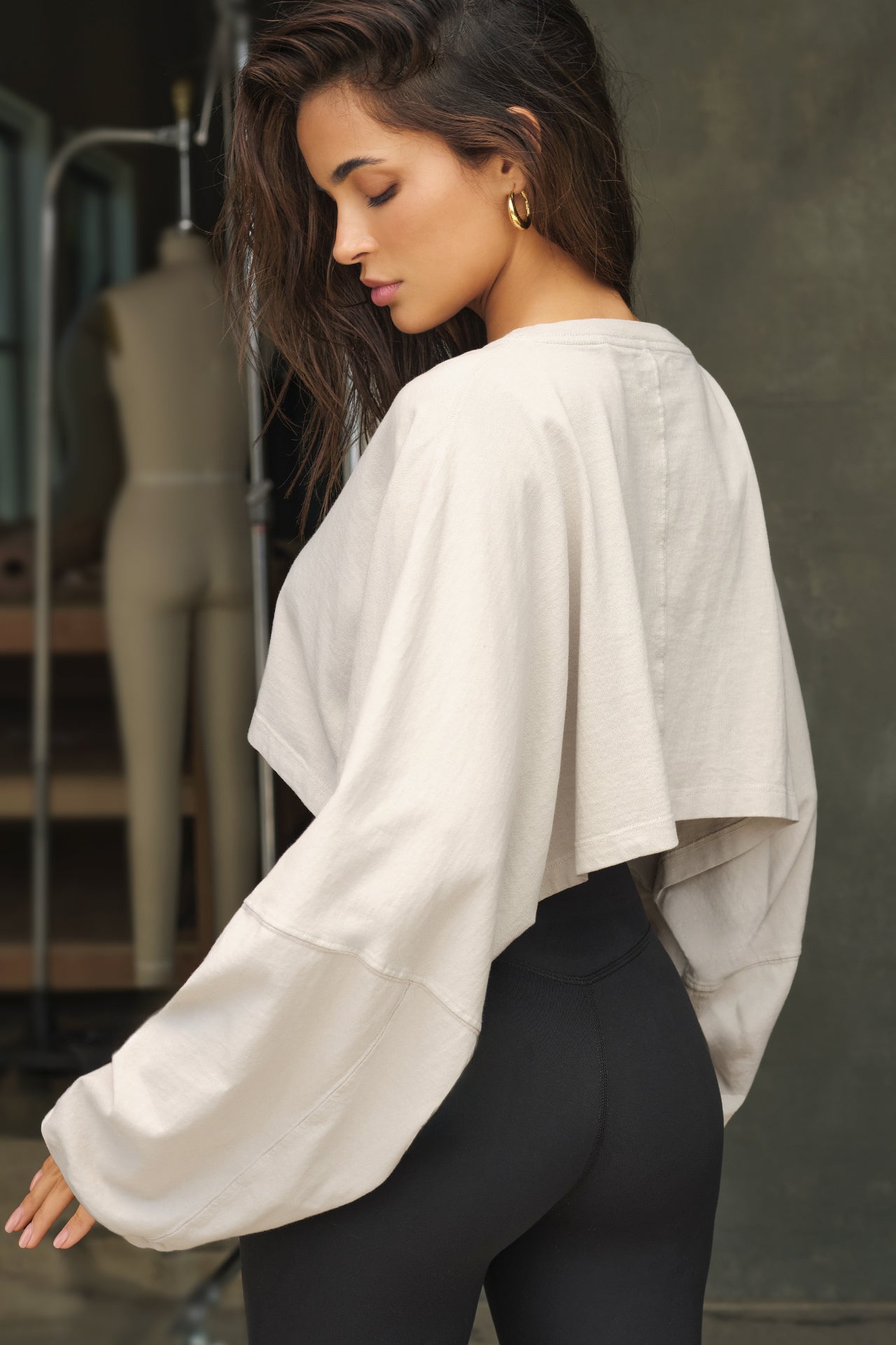 Back view of model posing in the cropped relaxed fit fog cotton Slouchy Crop Long Sleeve top with a crew neckline, dropped shoulders and oversized sleeves