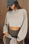 Front view of model posing in the cropped relaxed fit sandstone cotton Slouchy Crop Long Sleeve top with a crew neckline, dropped shoulders and oversized sleeves