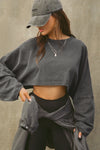 Front view of model posing in the cropped relaxed fit washed black cotton Slouchy Crop Long Sleeve top with a crew neckline, dropped shoulders and oversized sleeves