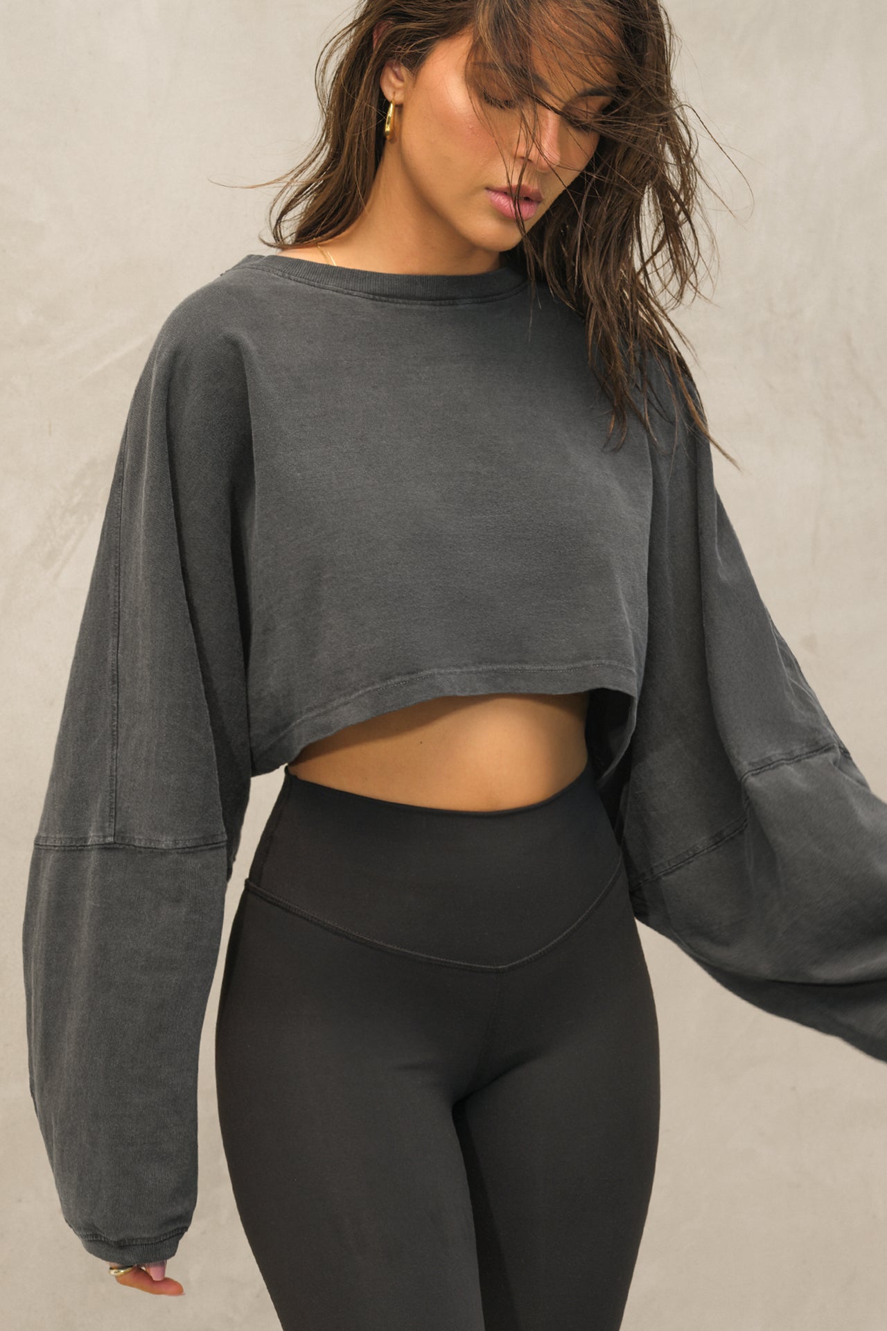Front view of model posing in the cropped relaxed fit washed black cotton Slouchy Crop Long Sleeve top with a crew neckline, dropped shoulders and oversized sleeves