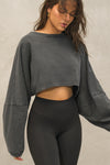 Front view of model posing in the cropped relaxed fit washed black cotton Slouchy Crop Long Sleeve top with a crew neckline, dropped shoulders and oversized sleeves