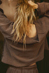 Back view of model posing in the oversized cedar french terry Slouchy Pullover Sweatshirt with a wide, off-the-shoulder neckline and a JOAH BROWN logo patch on the right sleeve, which she is wearing inside out