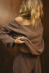Side view of model posing in the oversized cedar french terry Slouchy Pullover Sweatshirt with a wide, off-the-shoulder neckline and a JOAH BROWN logo patch on the right sleeve, which she is wearing inside out