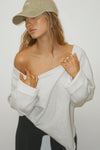 Front view of model posing in the oversized pearl grey french terry Slouchy Pullover Sweatshirt with a wide, off-the-shoulder neckline and a JOAH BROWN logo patch on the right sleeve