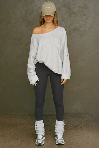 Full body frront view of model posing in the oversized pearl grey french terry Slouchy Pullover Sweatshirt with a wide, off-the-shoulder neckline and a JOAH BROWN logo patch on the right sleeve