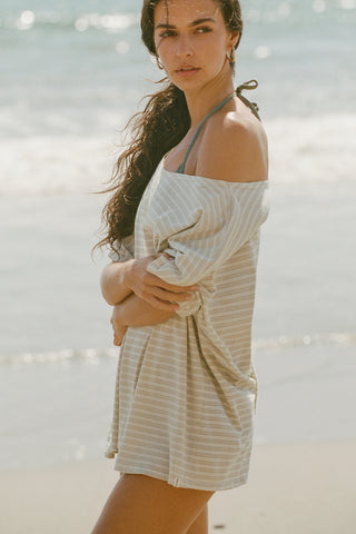 Side view of model posing on the beach in the oversized sage stripe classic cotton Slouchy Tunic Tee with a wide scoop neckline that can be worn off the shoulder