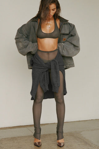 Full body front view of model posing in the sheer high-waisted graphite mesh Split Hem Legging with gathered ankles, exposed seams and button closures at the leg opening