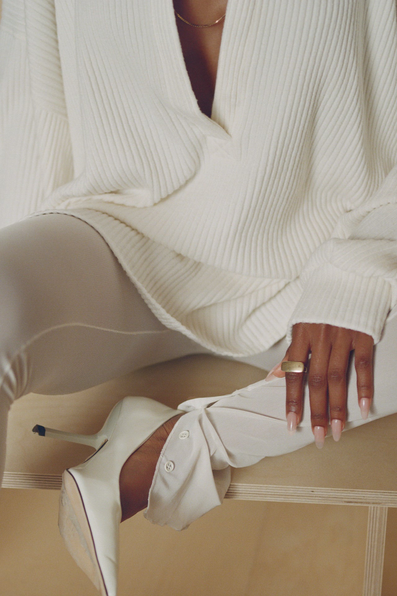 Close up detail front view of model posing in the sheer high-waisted porcelain mesh Split Hem Legging with gathered ankles, exposed seams and button closures at the leg opening