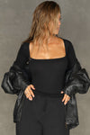 Front view of model posing in the fitted and stretchy black rib Square Neck Long Sleeve top with a wide square neckline
