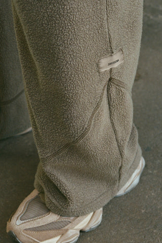 Close up detail side view of the curved seam details and JOAH BROWN logo patch of the relaxed-fit oakmoss sherpa Straight Leg Sweatpant 