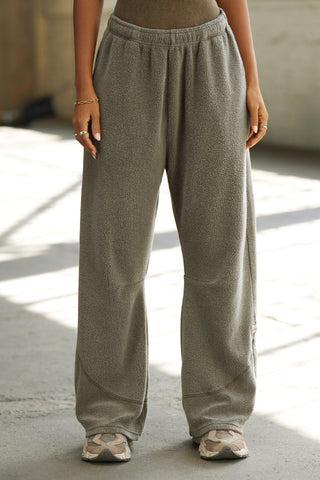 Front view of model from the waist down posing in the relaxed-fit oakmoss sherpa Straight Leg Sweatpant with a straight-leg silhouette, elastic waistband, side pockets, curved seam details and a JOAH BROWN logo patch