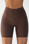 Close up front view of model from the waist down wearing the soft stretchy high-waisted sueded umber Biker Short with a wide waistband