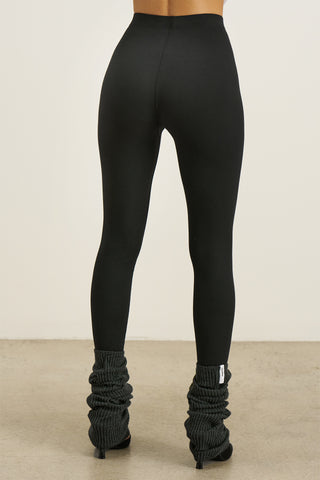 Back view of model from the waist down posing in the sleek and stretchy full length sueded onyx The Body Legging with a mid-rise elastic waistband