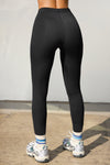 Back view of model from the waist down wearing the sleek and stretchy full length sueded onyx The Body Legging with a mid-rise elastic waistband