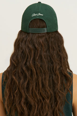 Back view of model posing in the structured six-panel  alpine The Classic Cap with a curved brim, adjustable back strap and an embroidered front and back Joah Brown logo