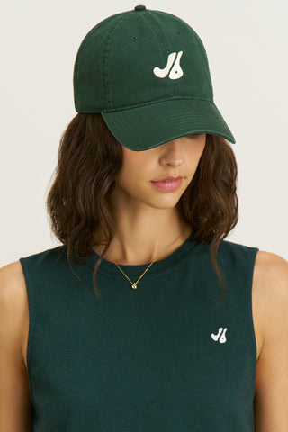 Front view of model posing in the structured six-panel  alpine The Classic Cap with a curved brim, adjustable back strap and an embroidered front and back Joah Brown logo