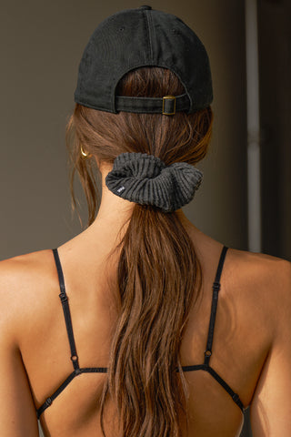 Back view of model wearing the six-panel black Signature Cap with a curved brim and adjustable strap