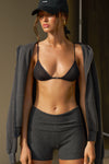 Front view of model posing the sheer, minimal coverage black mesh Triangle Bralette with thin and glossy adjustable elastic straps
