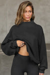 Front view of model posing in the comfortable black french terry Turtleneck Sweatshirt pullover with a side split in the collar and a slightly oversized fit
