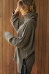 Side view of model posing in the relaxed and slouchy tunic-style army luxe knit Turtleneck Tunic with dropped shoulders, side slits and adjustable ties for a customized shape