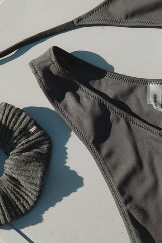 Flay lay view of the Joah Brown in V Cut Bikini Bottom and the ink luxe knit Knit Scrunchie