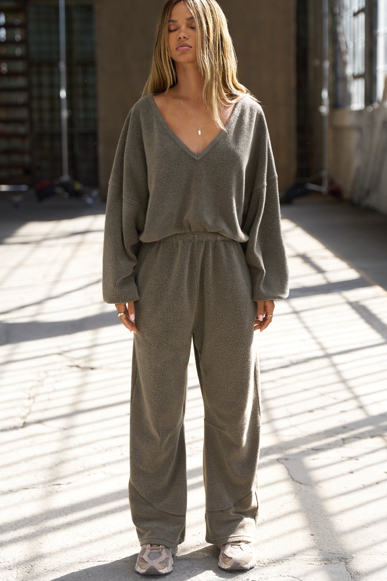 Full body front view of model posing in the slouchy oakmoss sherpa V Neck Pullover sweatshirt with a wide V-neckline that can be worn on or off the shoulders.