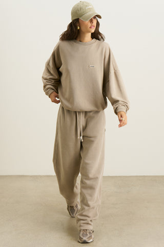 Full body front view of model posing in the relaxed fit sand french terry Varsity Crew Pullover sweatshirt with a crew neckline, dropped shoulders and a Joah Brown logo patch at the chest