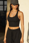 Front view of model posing in the fitted stretchy cropped black flexrib Varsity Tank Bra with a scoop neckline