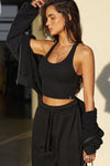 Side view of model posing in the fitted stretchy cropped black flexrib Varsity Tank Bra with a scoop neckline