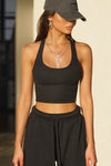Front view of model posing in the fitted stretchy cropped black flexrib Varsity Tank Bra with a scoop neckline
