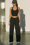 Full body front view of model posing in the fitted stretchy cropped black flexrib Varsity Tank Bra with a scoop neckline
