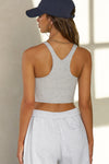 Back view of model posing in the fitted stretchy cropped pearl grey flexrib Varsity Tank Bra with a racerback silhouette
