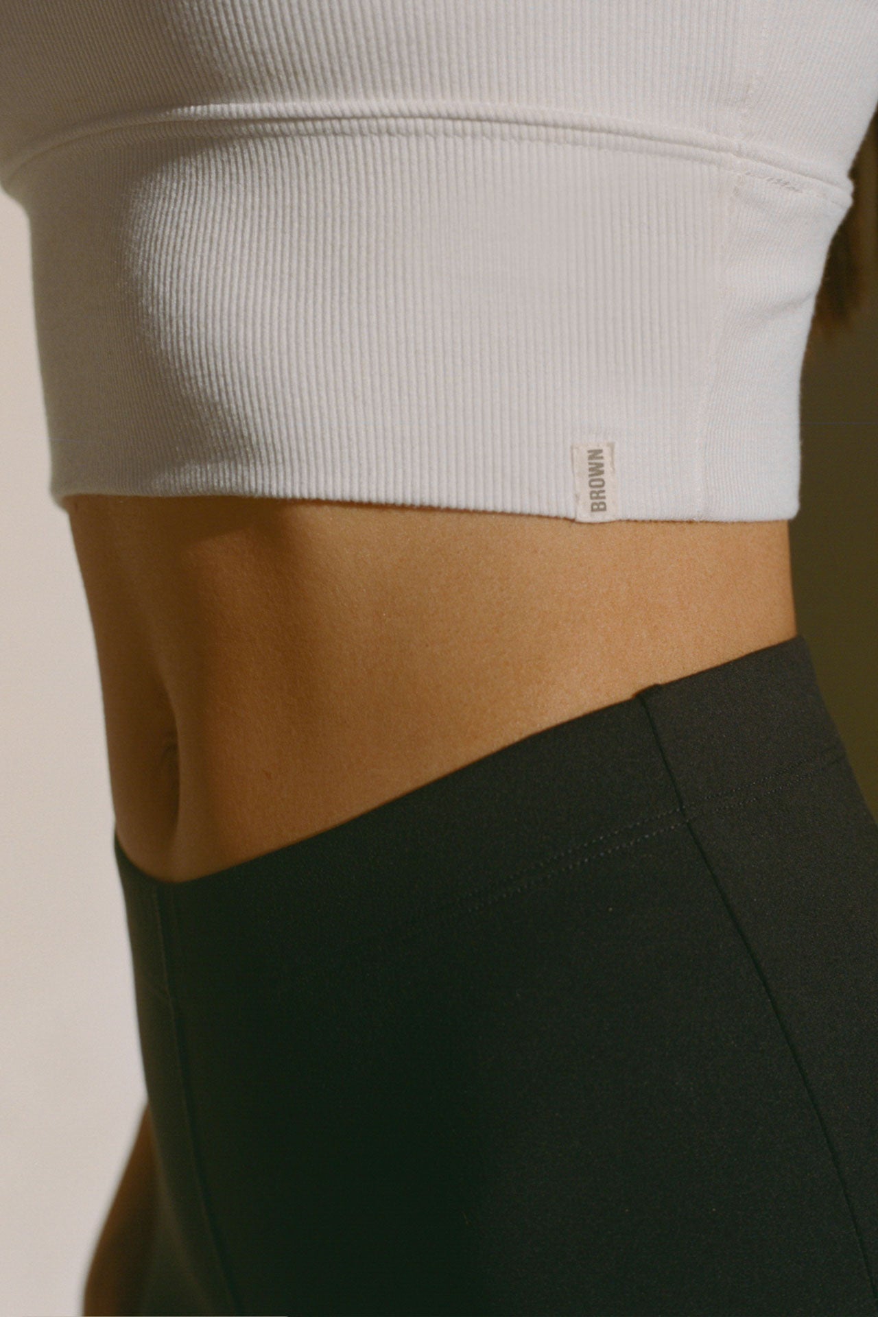 Close up detail side view of the fitted stretchy cropped white flexrib Varsity Tank Bra with a scoop neckline