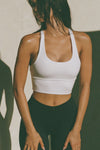 Front view of model posing in the fitted stretchy cropped white flexrib Varsity Tank Bra with a scoop neckline